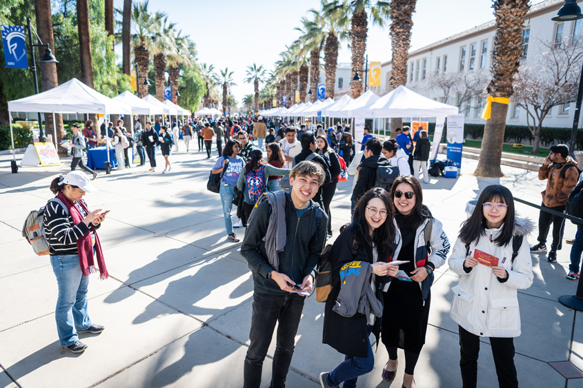 Students smile and pose on a busy paseo during Weeks of Welcome event.