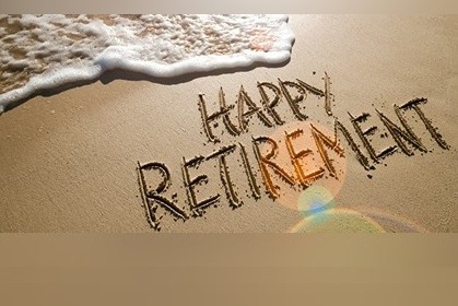 photo shows phrase "HAPPY RETIREMENT" written in the sand at a beach