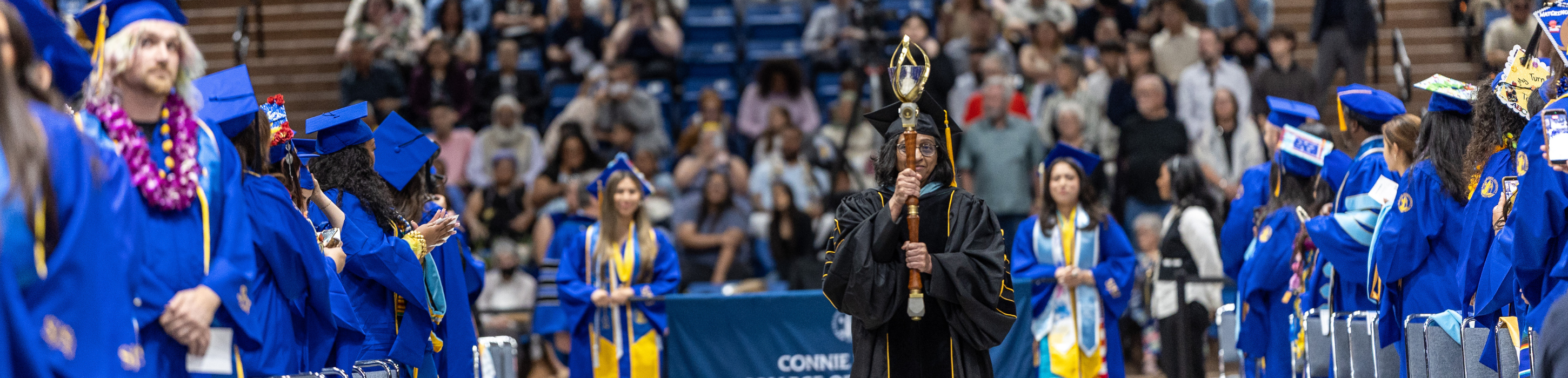 Mace bearer walking down the center aisle at a Commencement ceremony