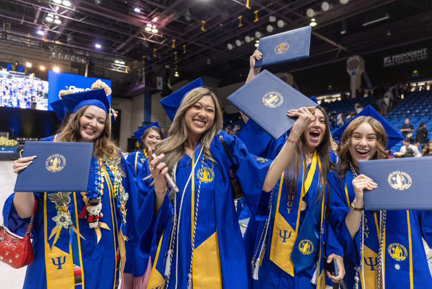 Graduating students holding up their diplomas