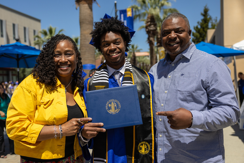 Parents posing for a photograph with their graduating Spartan