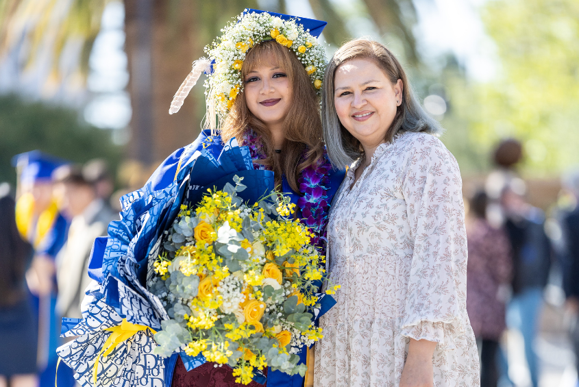 Student and parent posing for a photograph while wearing flower leis.