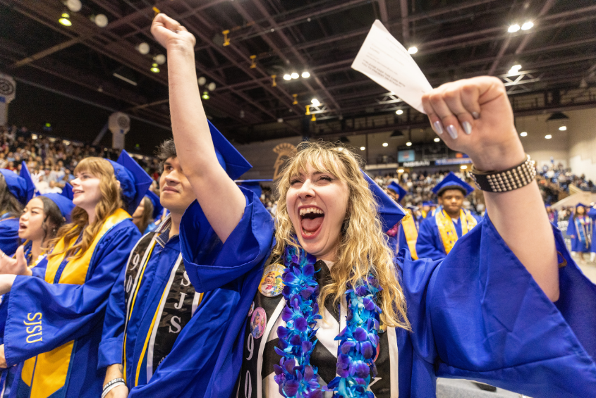 Graduating student cheering on the floor of the event center.