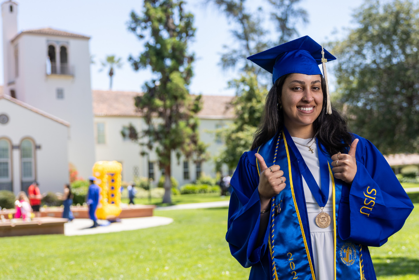 Student posing for a photo showing a thumbs-up hand sign.