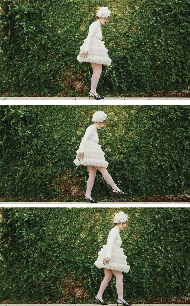 A person in a white, textured outfit and hat walks in front of a green hedge, captured in three sequential frames.