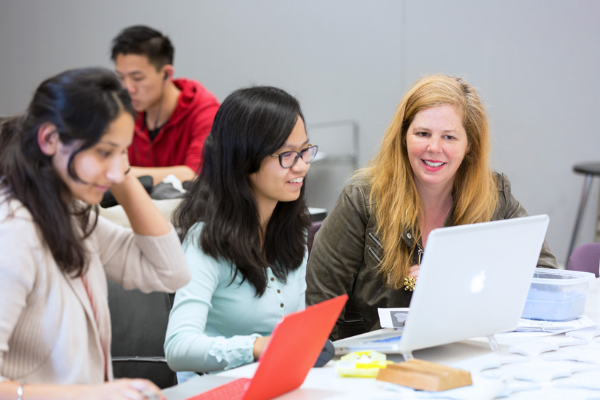 A professor working on the computer with two other students.