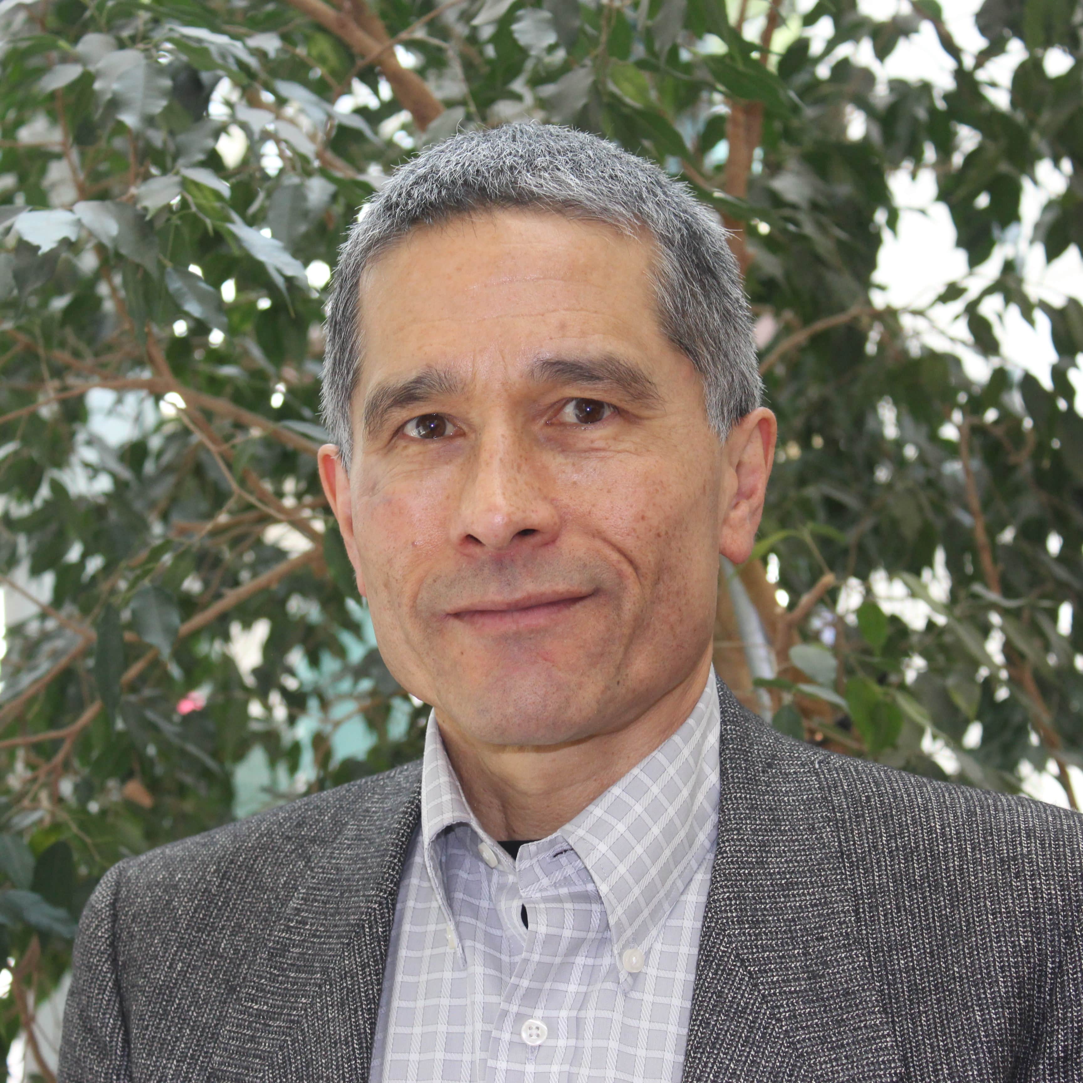 Headshot of interim dean and TED faculty david whitenack with green leaves in background