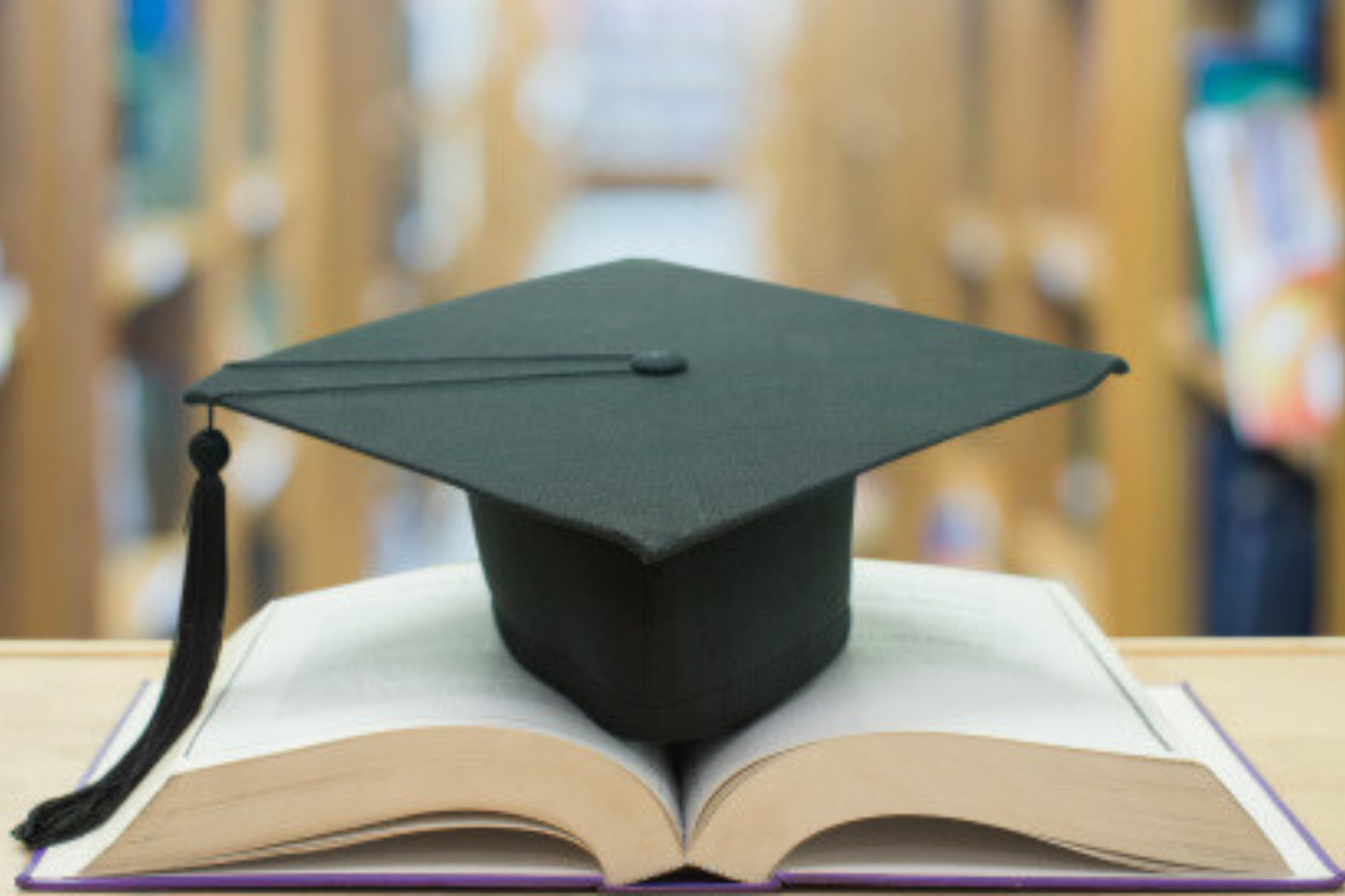 Graduate cap placed atop an open textbook