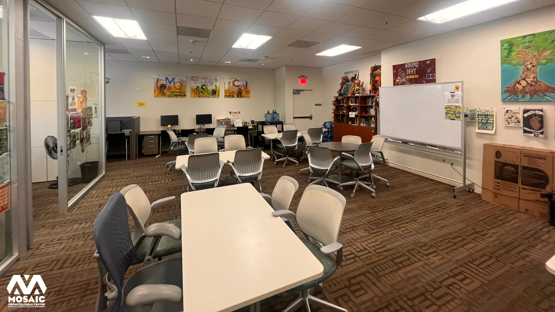 mosaic lounge with tables, chairs, whiteboard, and artwork on the wall