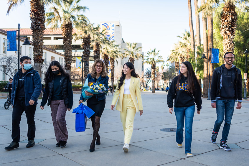 President Teniente-Matson with students walking down the paseo on a bright sunny day.