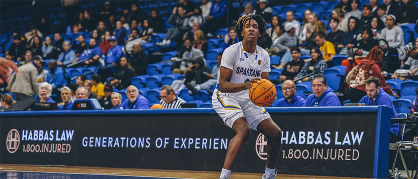 An SJSU basketball player hunches down as he is about to throw the ball.