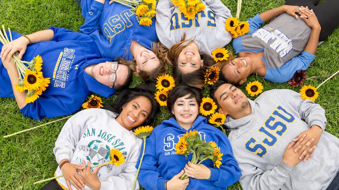 happy smiling students laying on grass