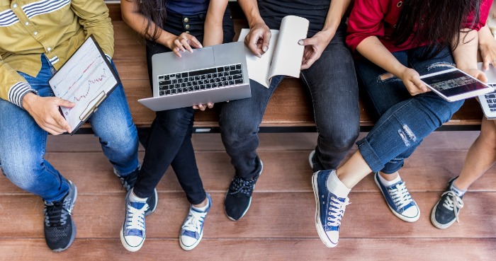 Top view of various students using laptops, tablets, and books