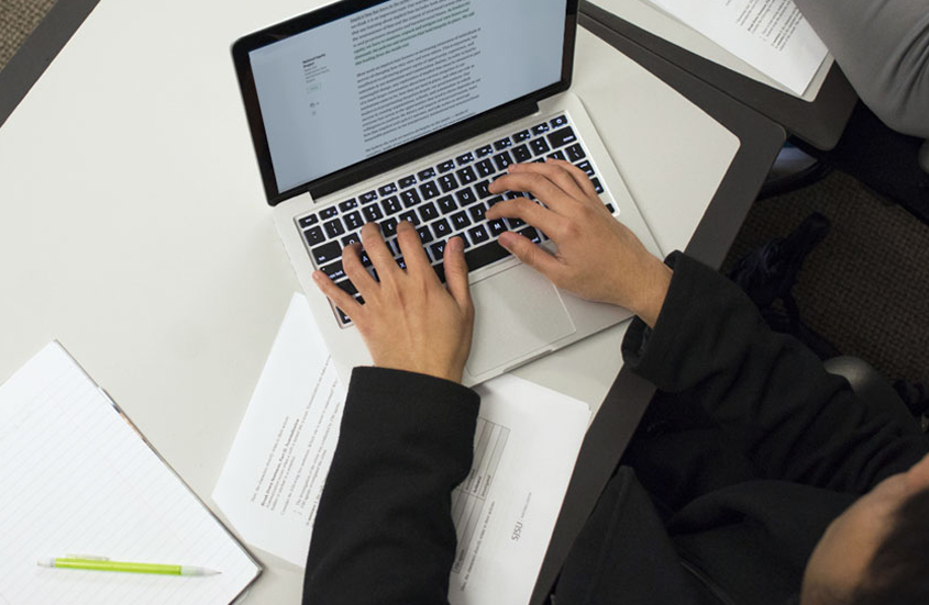 Student typing on a laptop.